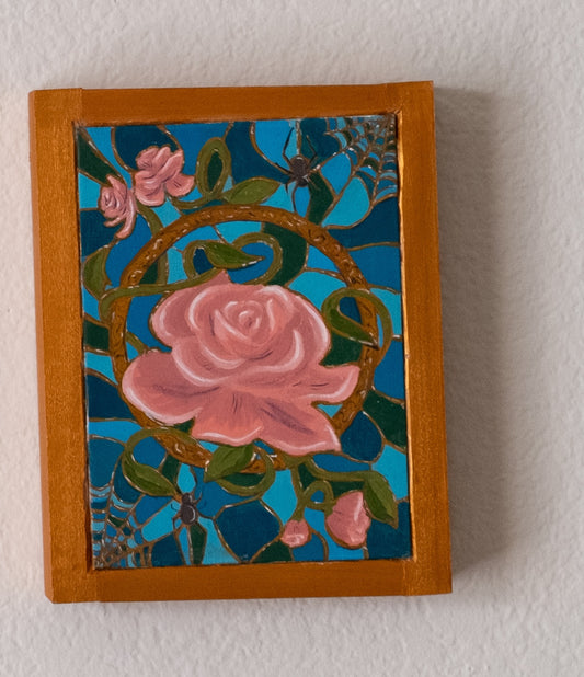 Decorative framed oil painting artwork with pink roses, green leaves, and spider webs on a blue background.