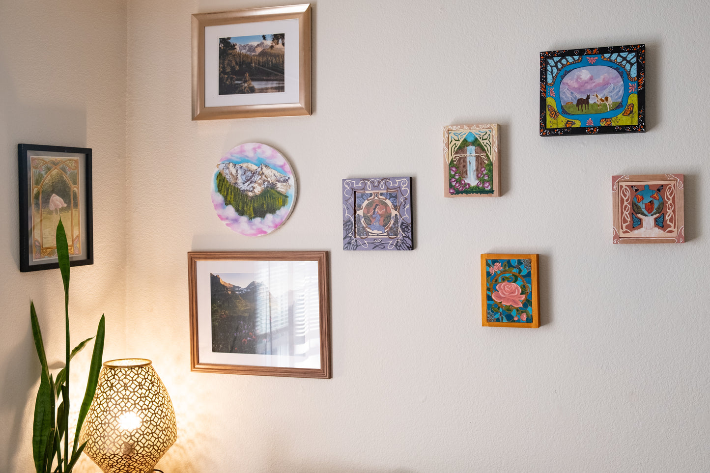 Painting of horses in a mountainous landscape with a colorful border featuring butterflies and flowers. gallery wall